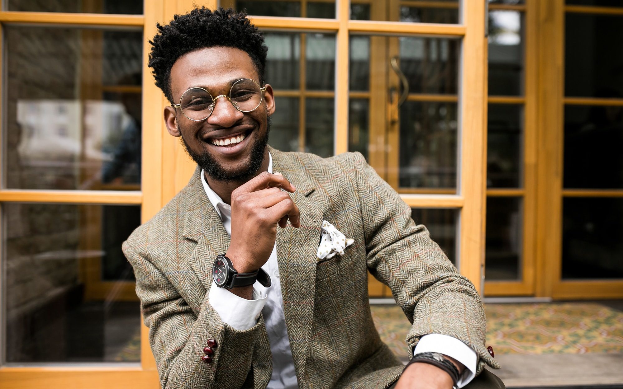 Male model wearing a costume with fake glasses and heavy tweed coat smiling