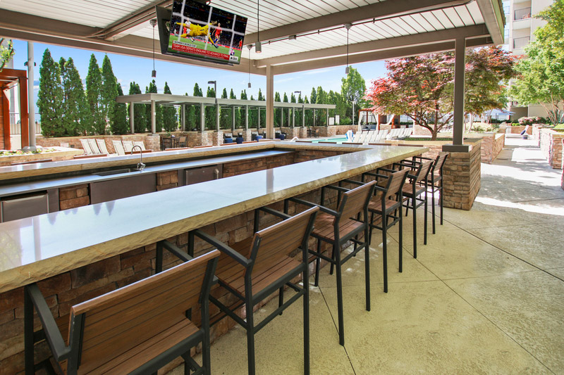 Ourdoot bar by the pool with flat screen TVs and long bar seating