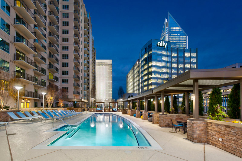 Night shot of lighted pool with lounge seating ,covered table seating and downtown views