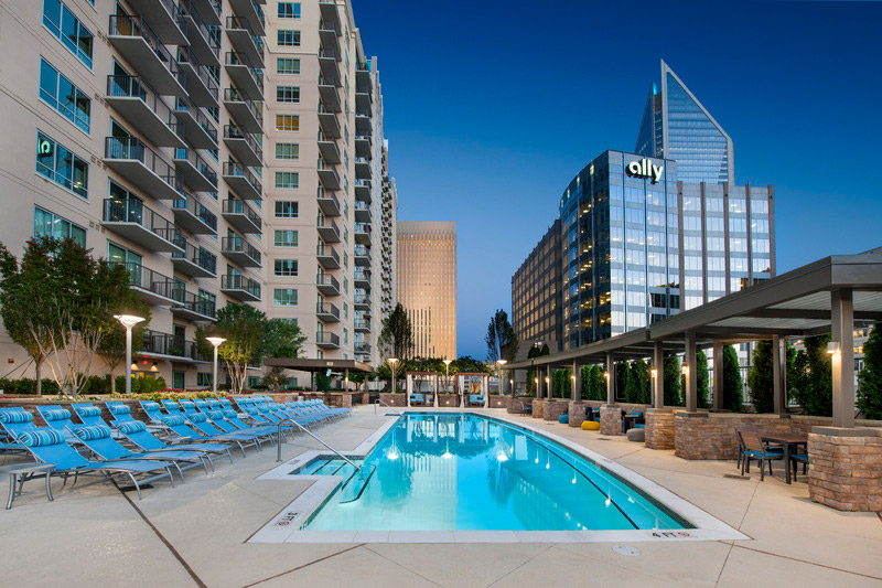 Resort like pool with lounge seating, covered table seating and downtown views