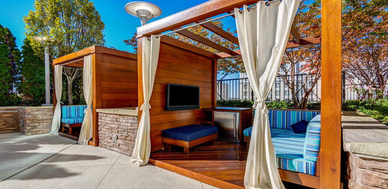 Pool cabanas with plush bench seating, flat screen TV, and mini fridge