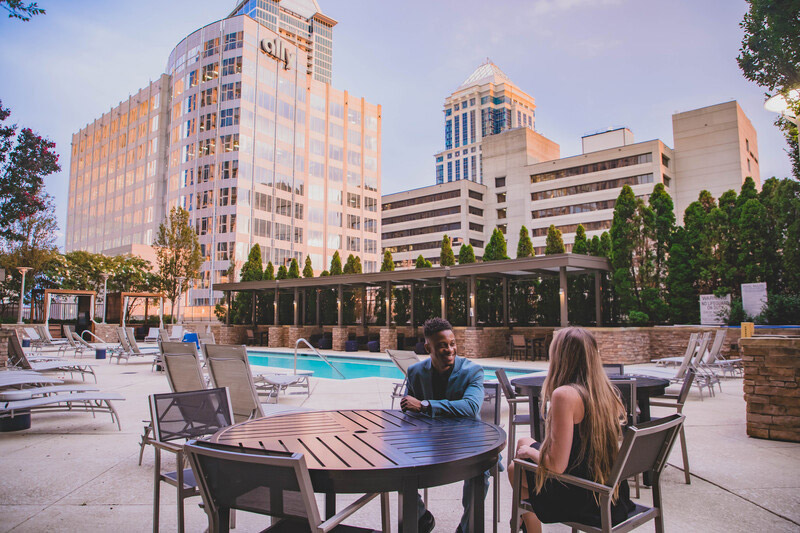 Couple talking in outdoor courtyard with pool and downtown views